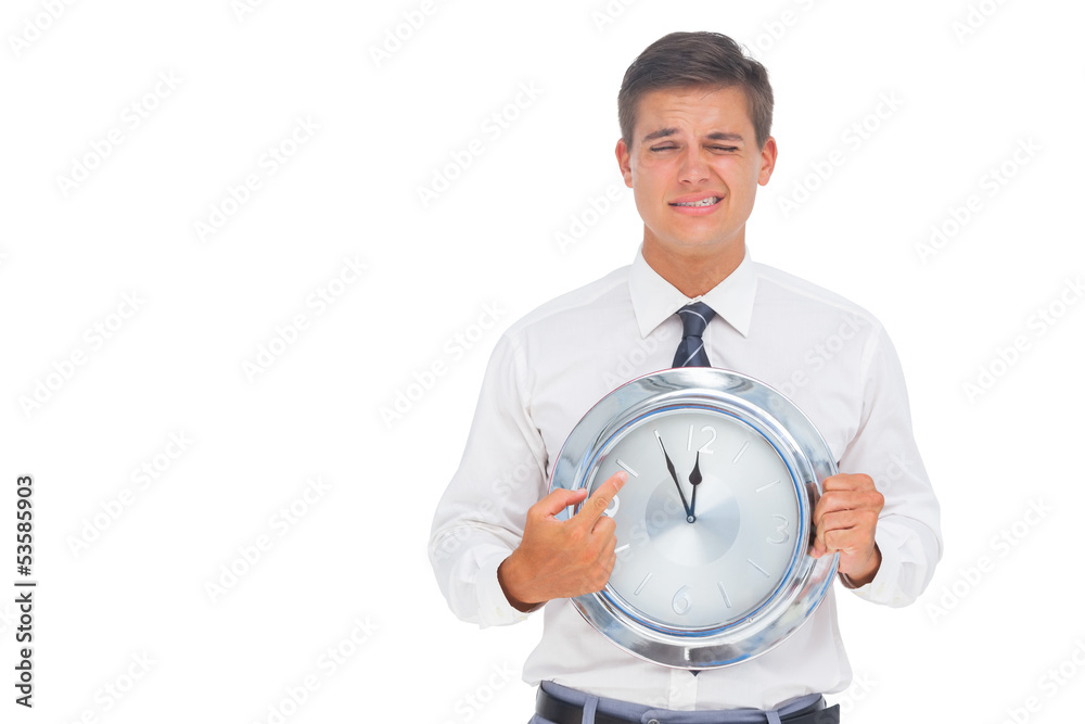 Worried businessman holding and pointing at clock Worried businessman holding and pointing at clock