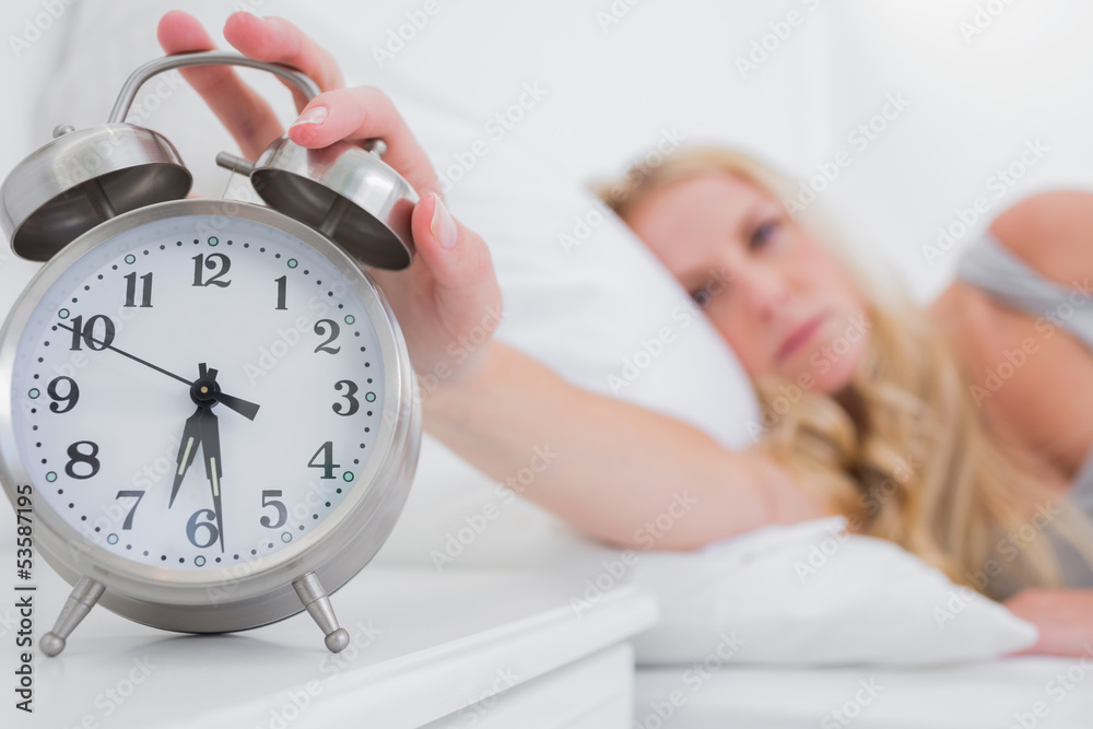 Tired woman turning off the alarm clock Tired woman turning off the alarm clock