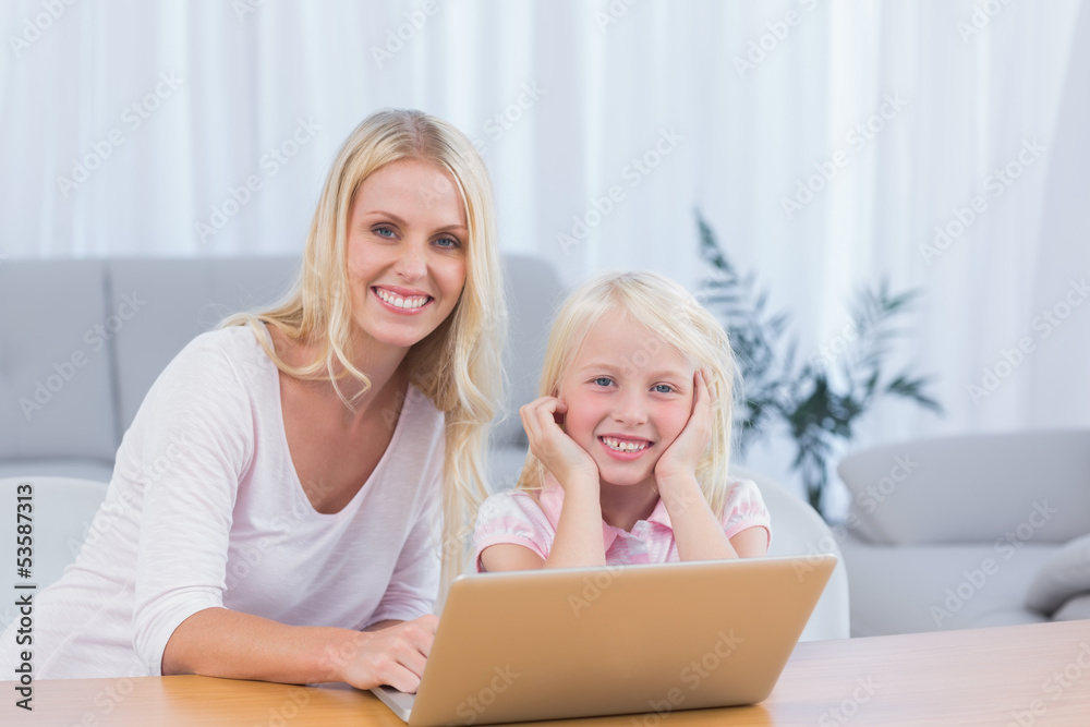 Smiling mother using laptop with her daughter Smiling mother using laptop with her daughter