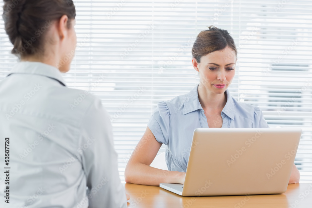 Businesswoman looking at laptop during an interview Businesswoman looking at laptop during an interview