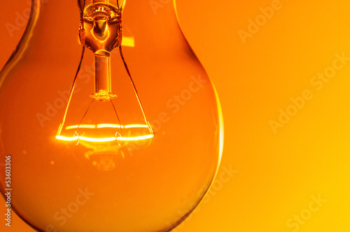 Close up glowing light bulb on orange background photo