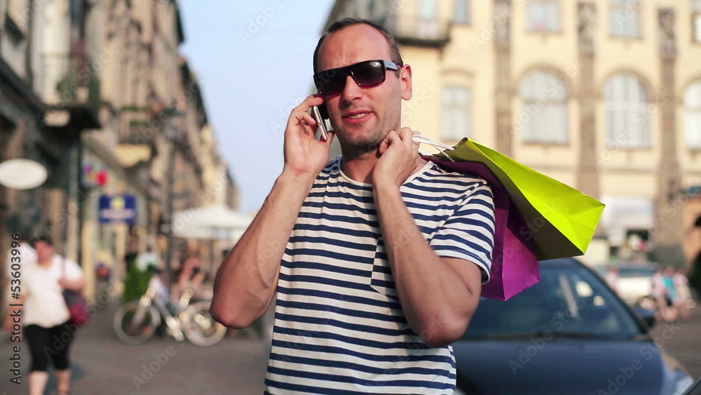 Man with shopping bags talking on cellphone in the city Man with shopping bags talking on cellphone in the city