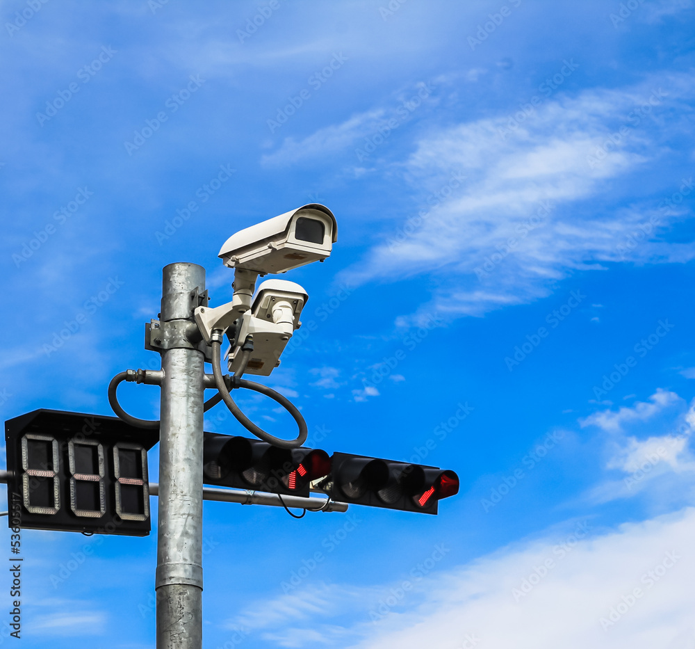 surveillance camera and traffic light against blue sky surveillance camera and traffic light against blue sky