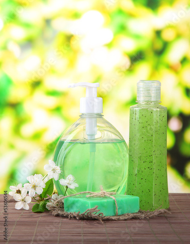 Cosmetics bottles and natural handmade soap on green background