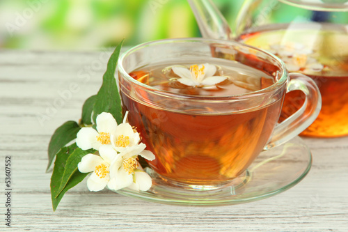 Cup of tea with jasmine, on wooden table, on bright background
