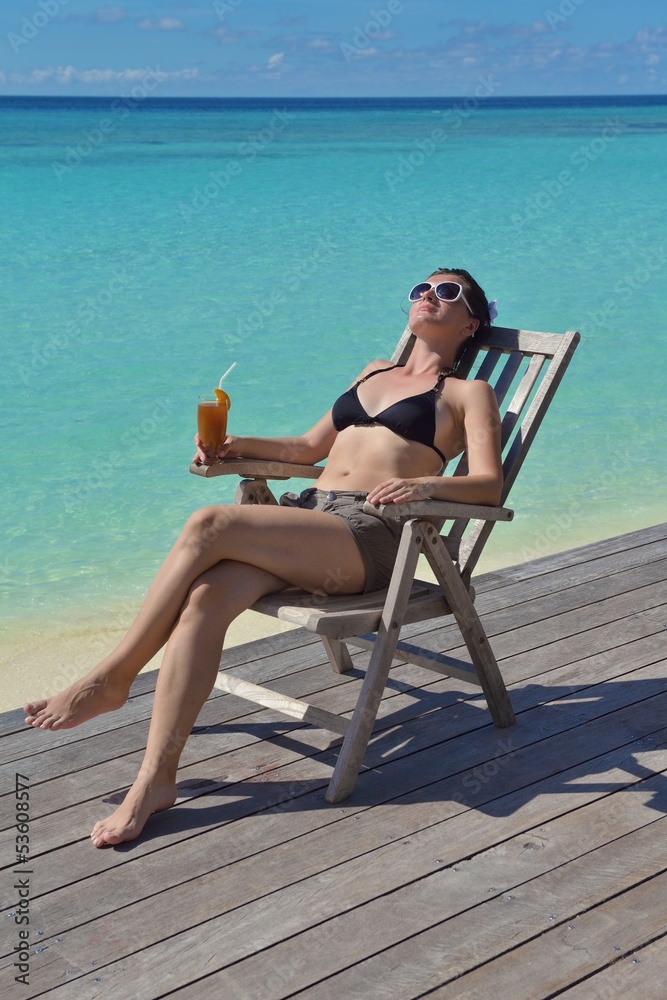 Beautiful young woman with a drink by the sea
