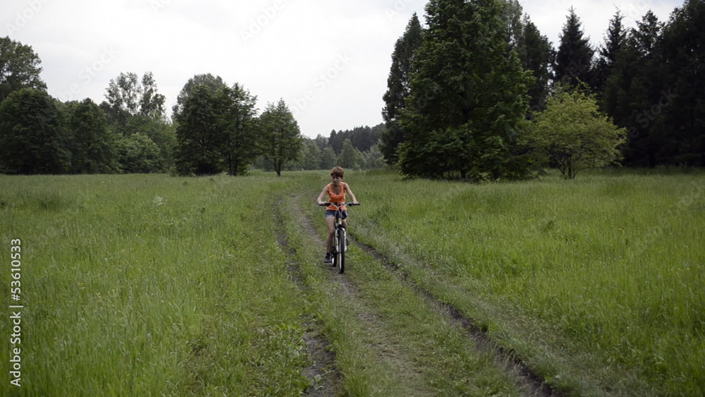 Woman with bicycle in summer field travels slowly Woman with bicycle in summer field travels slowly