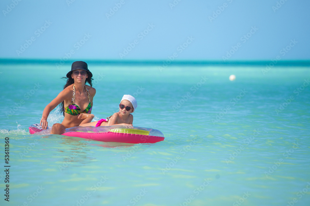 Obraz premium Young mother with young daughter on an air mattress in the sea