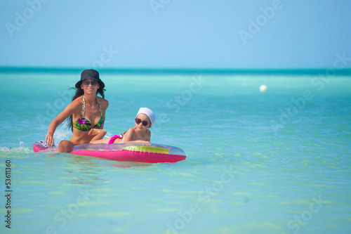 Young mother with young daughter on an air mattress in the sea