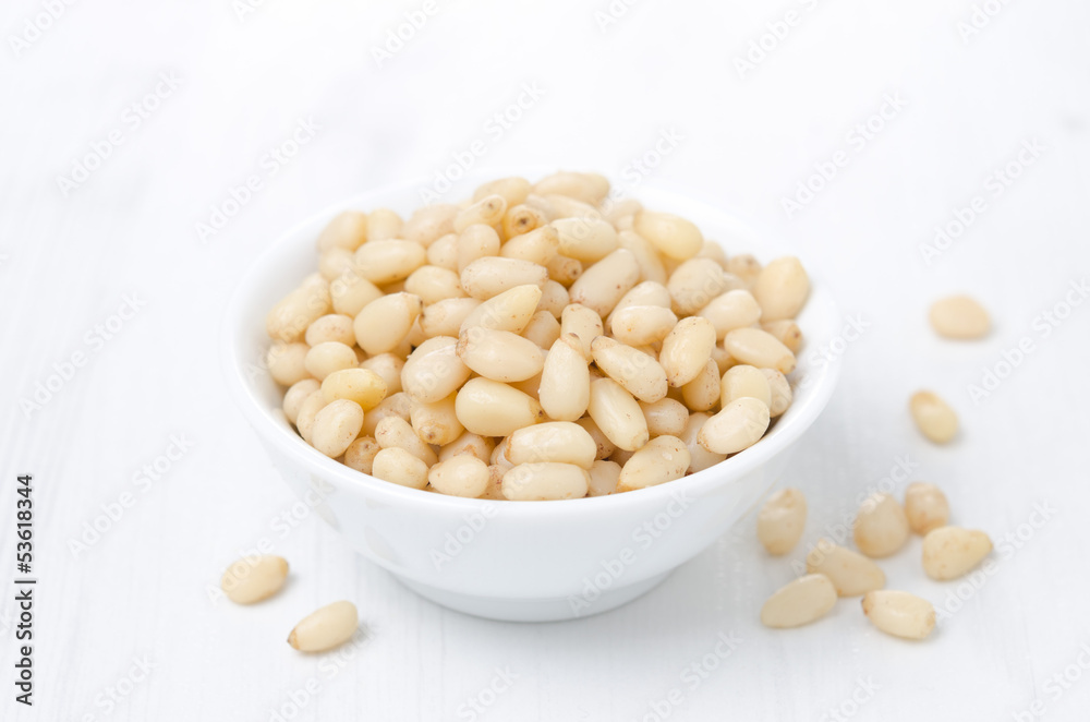 pine nuts in a bowl on a white background pine nuts in a bowl on a white background