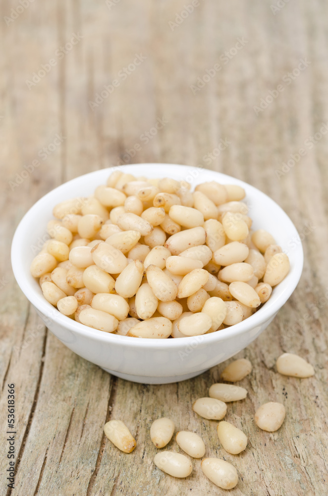 pine nuts in a bowl on wooden background pine nuts in a bowl on wooden background