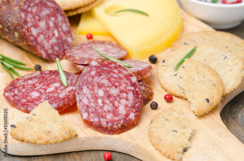 salami, cheese, crackers and spices on a cutting board