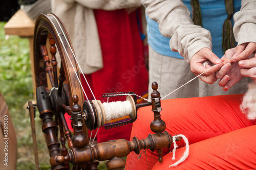 spinningwheel with hands making yarn from the wool photo