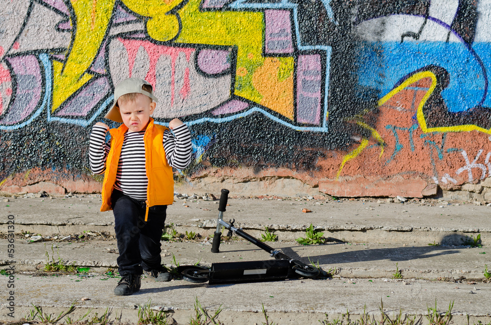 Obraz premium Cute little boy playing in front of graffiti
