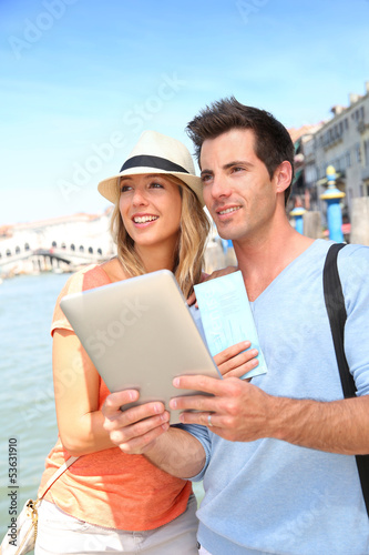 Couple standing by the Canal grande in Venice with tablet