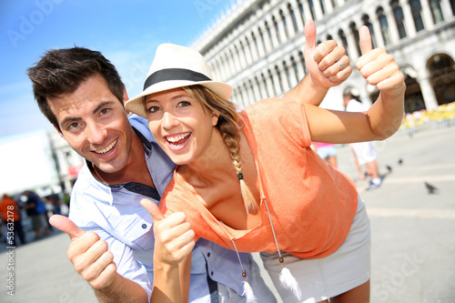 Cheerful couple showing thumbs up on San Marco Place