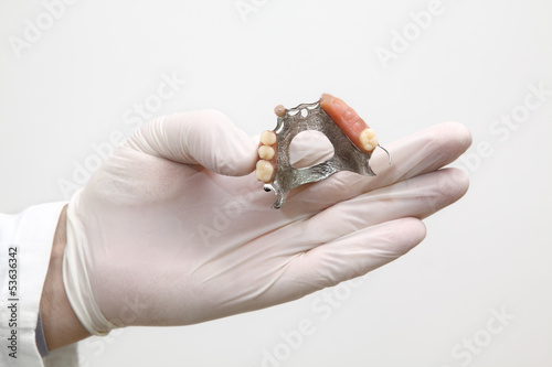 Dentist holding  artificial tooth in hand with gloves photo
