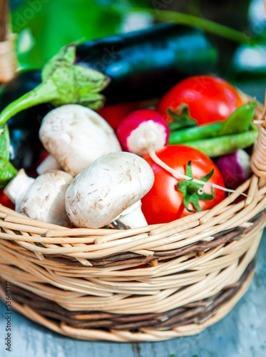 Fresh vegetables in a basket on wooden table