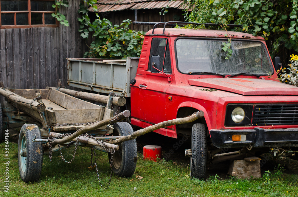 Old car and rustic carriage abandoned in a countryside yard Old car and rustic carriage abandoned in a countryside yard