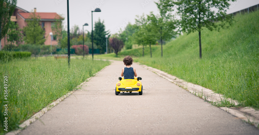 Young kid playing with toy car outdoors. Back view. Young kid playing with toy car outdoors. Back view.