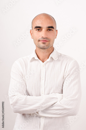 Portrait of a bald man dressed in white. Arms crossed. © luanateutzi