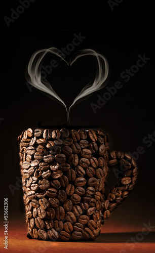 Cup of coffee beans with smoke in shape of heart