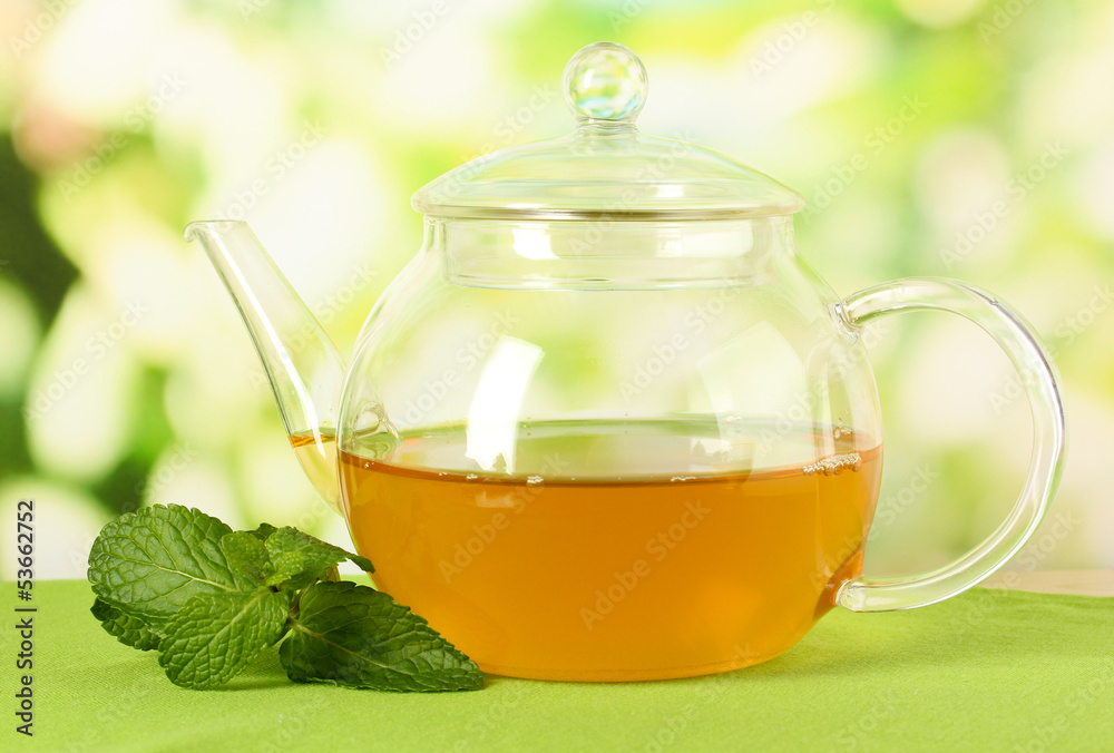 Teapot with mint on table on bright background Teapot with mint on table on bright background