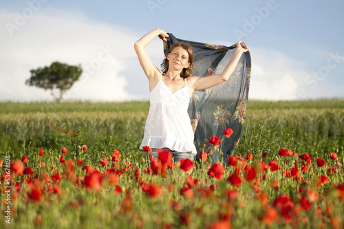 Young casual woman relaxing in poppy field