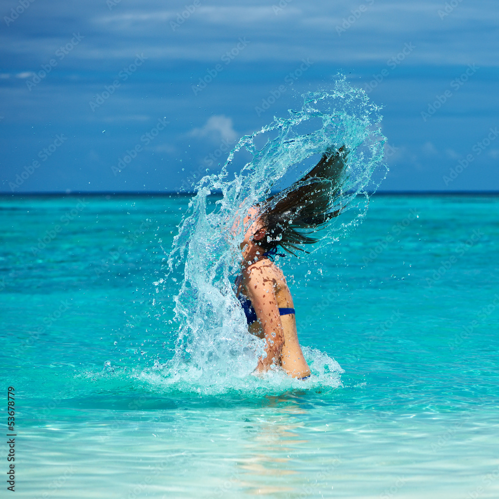 Woman splashing water with hair in the ocean