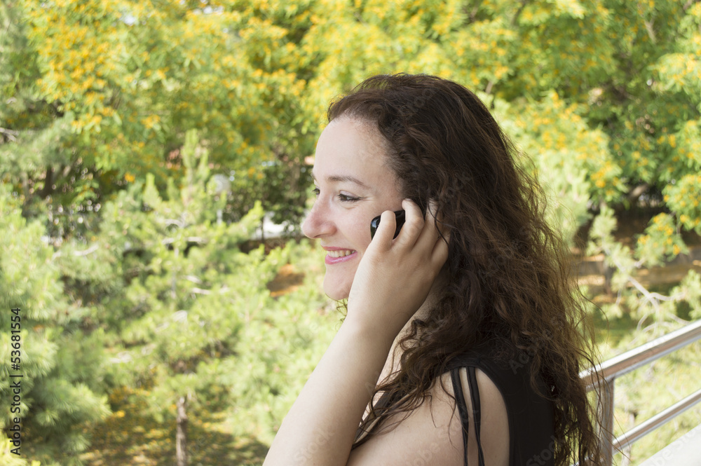 woman talking on a cell phone while overlooking the garden woman talking on a cell phone while overlooking the garden