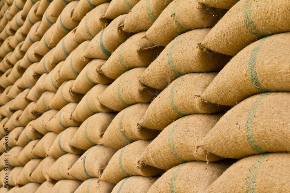 Old hemp sacks containing rice placed profoundly stacked.
