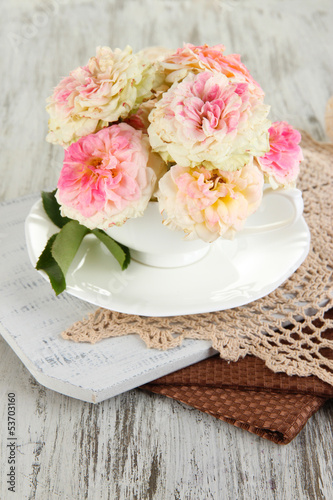 Roses in cup on napkins on  wooden background