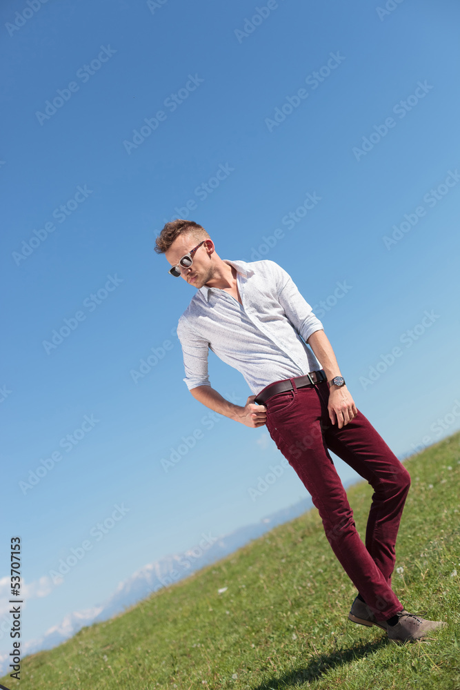 outdoor casual man holds his belt and looks away outdoor casual man holds his belt and looks away