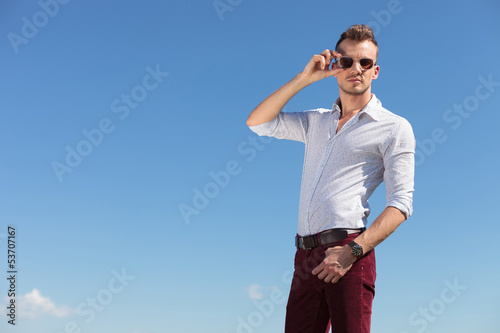 casual man adjusts his sunglasses outdoor