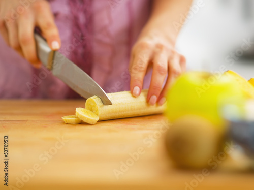 Closeup on woman cutting banana on cutting board