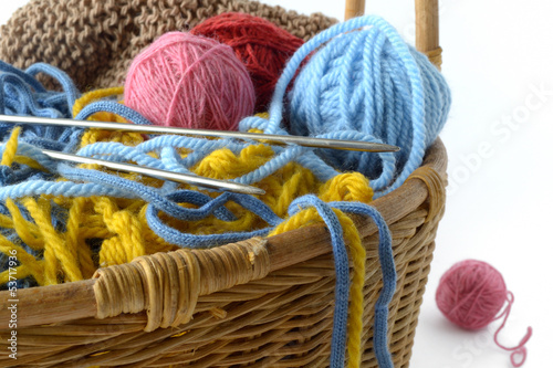 wicker basket with balls of yarn and knitting needles photo