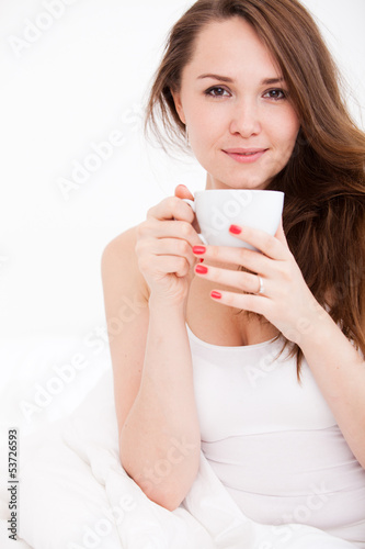 portrait of  woman in bed holding a cup