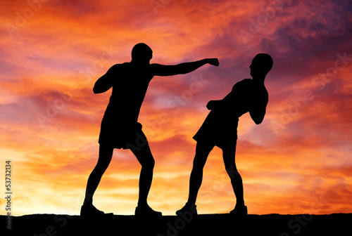 Silhouettes of two fighters on sunset background © es0lex