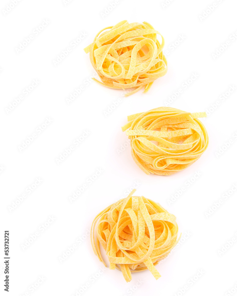 Three fettuccini pasta nests isolated on white.
