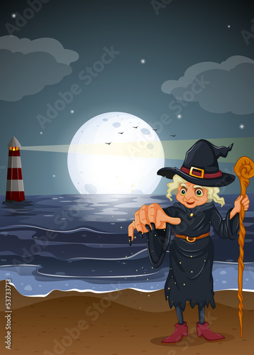 An old witch holding a stick at the beach