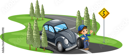 A boy repairing a gray car