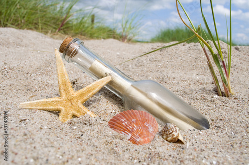 Flaschenpost mit Muschel, Seestern im Sand