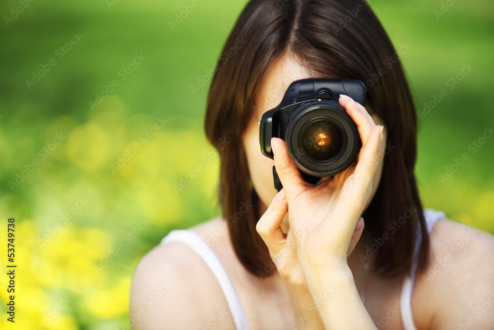 Image of young beautiful woman photographing in summer park