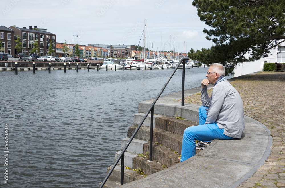man sitting and thinking near the water