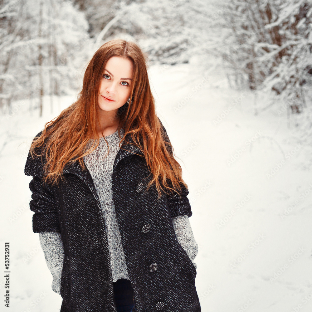 Outdoor winter portrait of beautiful longhaired woman posing in park dressed in black warm coat 