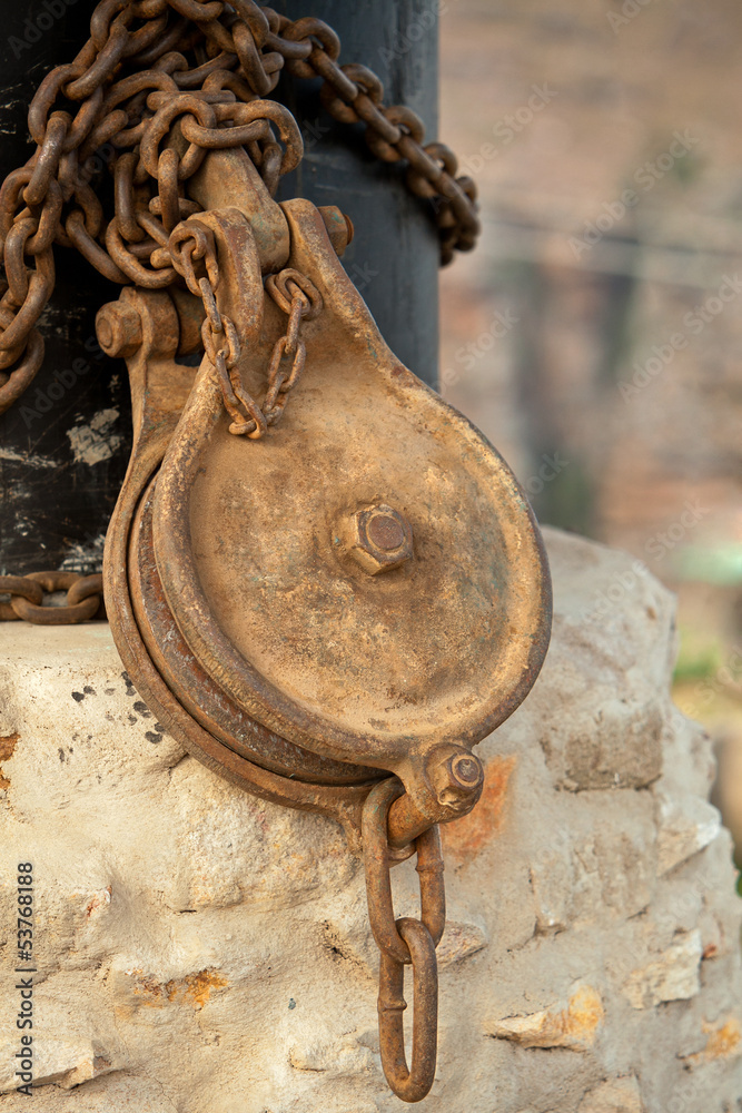 Rusted pulley chained to a pole Rusted pulley chained to a pole