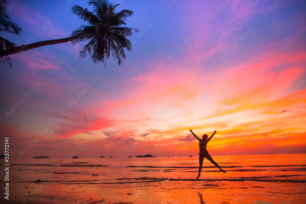 Young girl in a jump on the sea beach at sunset