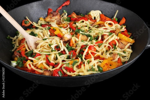 Noodles with vegetables on wok isolated on black