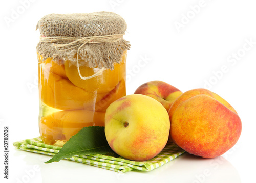 Jar of canned peaches and fresh peaches, isolated on white