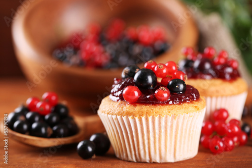 Tasty muffins with berries on wooden table